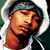 Pixelated static image of a person with orange skin tone wearing dark green headwear and black clothing, cropped to show upper body against white background.