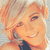 A pixelated image of a person with light brown hair and a dark top, smiling in a