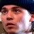 Pixelated close-up of a person's face with light skin tone, dark hair, and neutral expression against dark background.