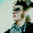 Pixelated image of a person with dark hair and sunglasses, wearing a checkered shirt, next to blue text on black and gray backgrounds.