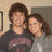 Two people stand close together in a room with beige walls and framed artwork; the right side shows text reading 'I belong together... May 8, 2005' over dark background.