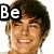 A pixelated image of a smiling person with brown hair, featuring text overlays that change across frames.