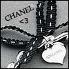 Black-and-white pixelated image of a Chanel-branded accessory with beaded straps and heart-shaped charms.