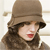 A pixelated image of a person wearing a brown bucket hat and a brown coat with long dark hair, red lips, and a light background.