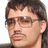 Pixelated close-up of a person with dark hair, glasses, and light skin wearing a black top against a white background.
