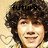 A pixelated image of a person with curly brown hair, smiling, with text overlays and a heart-patterned background.