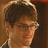 Pixelated image of a person with short brown hair and glasses on the left, next to pink pixelated text reading 'justin <3 bartha' on a solid brown background.