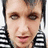 Pixelated close-up of a person's face with light skin tone, brown eyes, and dark hair, wearing black-and-white striped clothing against a white background.