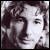 Pixelated grayscale portrait of a person with dark hair and neutral expression, displayed as static single-frame icon.