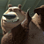 Pixelated image of a brown bear-like figure with a dark brown body and light brown face, wearing a dark blue collar, against a muted green background.
