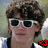 A person with curly brown hair and white sunglasses appears in six , each showing a different colored '43' text below the face