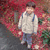 A child in a white jacket and blue pants stands on a path with red foliage background, showing subtle pose changes across frames.