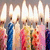 Pixelated image of multiple figures in colorful attire under bright vertical light sources, with a blurred background.