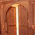 A static image of a wooden door with an arched top, partially open, revealing a bright light source behind it.