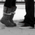 Black-and-white image of two people walking, one in boots and jeans, the other in dark pants and shoes, with a colorful star-shaped object in the foreground.