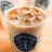 A pixelated image of a bubble tea drink with a dark blue tapioca base and light brown top layer, with text reading 'go starbuck' in black pixelated font.