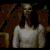 A woman in a white long-sleeve top and brown skirt appears in three sequential poses against a dark patterned background with golden accents.