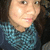 Pixelated close-up of a person with light skin wearing a blue patterned top against a dark background.