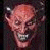 Pixelated image of a bald figure with horns and dark hair on the sides, set against a green background with pixelated text.