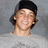 A pixelated image shows a person with dark hair wearing a black cap and gray shirt against a gray background, next to blue text on green.