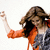 A pixelated figure with brown hair wears an orange jacket over a gray hoodie, raising one arm against a white background.