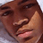 Pixelated close-up of a person's face with brown hair, showing eyes, nose, and mouth in a neutral expression against a light background.