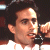 Static pixelated image of a person singing into a microphone with dark hair and light skin tone against a dark background.