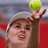 Pixelated static image of a tennis player holding a yellow ball above their head with one hand, wearing a white cap and red outfit against a blurred background.