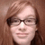 Pixelated portrait of a person with light brown hair and glasses against a solid brown background.