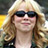 Static 48x48 pixel icon showing a person with long wavy hair wearing dark sunglasses and a light-colored top, set against a blurred background with yellow and white tones.