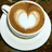 A cup of coffee with heart-shaped latte art on a white saucer against a pink background, accompanied by text reading 'Hot Chocolate and Muffins' in light blue pixelated font.