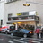 Pixelated static image of a theater facade with a marquee, multiple windows, and a street scene including a red vehicle and pedestrians.