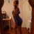 A woman in a blue dress stands in a room with wooden flooring and a small table, her pose shifting slightly across frames.