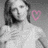 A grayscale image of a woman with shoulder-length dark hair wearing a light-colored top, holding her hands near her chest, with two pink heart symbols on the right side.