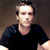 Pixelated static image of a person wearing dark clothing against a gradient background with visible dithering and low-resolution rendering artifacts.