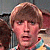 A 2x2 contact sheet of a pixelated animated icon featuring a young man with light brown hair in three frames, with text "Look what I can do!" on the bottom-left frame over a colorful striped background.