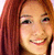 A static pixelated image of a person with long reddish-brown hair, light skin tone, and visible facial features including eyes, nose, mouth, and teeth.