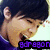 Pixelated image of a person with dark hair and light skin, wearing purple clothing, making a hand gesture near their face.