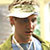 Pixelated static image of a person's face with visible facial features and clothing, set against a light background with greenish elements.
