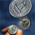 A hand holds a silver button against a blue background with two additional buttons floating above it.