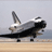 Static pixelated image of a space shuttle on a runway with gray sky background, rendered in low-resolution 48x48 pixels.
