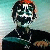Pixelated static image of a stylized character with dark hair, white facial markings, and a black outfit against a gradient background.