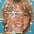 Pixelated image of a smiling person with light brown hair against blue background, partially obscured by white digital artifacts.