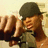 A pixelated image of a person wearing a dark cap and light shirt, with a hand raised near the face, set against a green background with text variations.