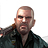 Pixelated static image of a bald man with dark eyebrows and mustache wearing black jacket over dark shirt, cropped to show upper torso against white background.