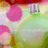 Pixelated image of pink flowers with green stems and leaves against a light background, featuring soft pastel colors including purple and yellow accents.