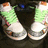 Two green and white sneakers with orange accents on a dark background, showing slight animation changes in the right shoe's position.