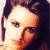 Pixelated close-up of a person's face with dark hair, warm-toned skin, and visible eye and nose features against a dark background.