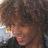 orange and gray with pixelated text overlays, featuring a partial image of a person with curly hair in the top-left corner