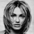 Black-and-white pixelated static image of a person's face with shoulder-length hair, rendered in low-resolution grayscale with visible dithering and anti-aliased edges on the hair and facial features.